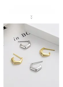 Macro shot of silver and gold geometric C-shaped earrings with S925 hallmark engraving