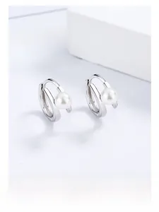 Primo piano degli orecchini a cerchio in argento S925 con perle su sfondo decorativo