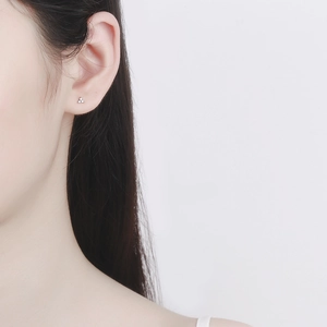 Minimalist S925 silver three-zircon clover stud earrings worn on female model's ear