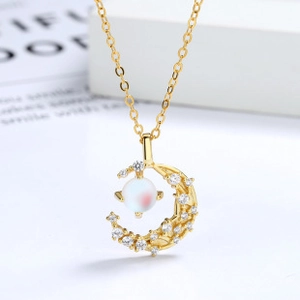 Macro detail of crescent moon pendant necklace with pavé zircons and aurora pearl stone