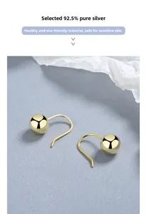 Close-up of minimalist gold-plated 925 sterling silver ball drop earrings on white paper