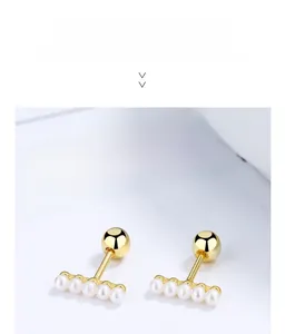 Detailed close-up of golden bar stud earrings with five small pearls and screw-back closure