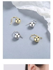 Polished silver and gold ball hook earrings shown in a detailed flat lay and on a model