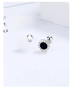Detail of round silver stud earrings with black inlay and engraved Roman numerals