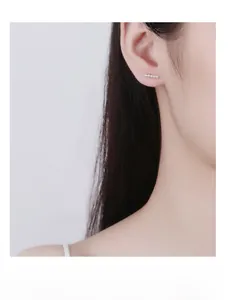 Close-up of minimalist 925 silver stud earrings with five small pearls worn on ear