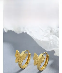 Detail of gold butterfly earrings with sandblasted texture and multi-layer plating finish