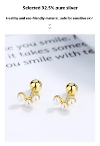 Dettaglio di orecchini in argento 925 dorato con tre delicate perle bianche