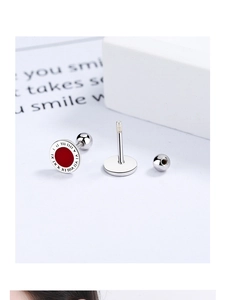 Macro detail of silver stud earring with red enamel center and Roman numeral engravings