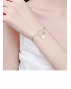 Detail view of a double-layer S925 sterling silver star bracelet on a woman's wrist