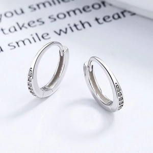 Detail of 925 sterling silver hoop earrings with shiny white zircon stones inlay