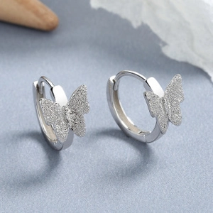 Macro detail of 925 sterling silver butterfly hoop earrings with frosted textured finish