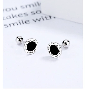 Macro detail of silver stud earrings with black enamel face and Roman numeral engraving