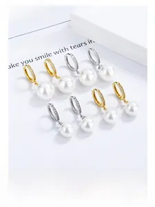 Detailed close-up of pearl hoop earrings featuring pavé rhinestones in gold and silver