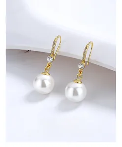 Gros plan de boucles d'oreilles en perles avec crochets dorés et zircons sur céramique