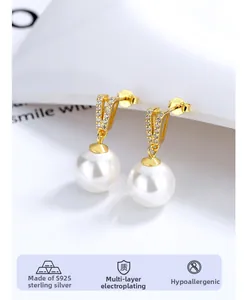 Détail macro de boucles d'oreilles perles goutte avec argent S925 doré et zircons
