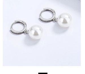 Macro shot of S925 sterling silver stamp and zircon pavé on hoop earrings with round pearl