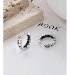 Gros plan de boucles d'oreilles créoles en argent S925 avec motifs en relief de pièces