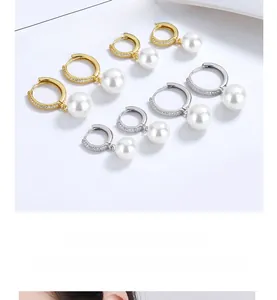 Close-up of four pairs of gold and silver pearl hoop earrings on a minimalist card