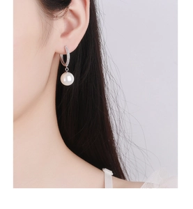 Close-up of 925 silver hoop earrings with pavé diamonds and white pearl drops on model