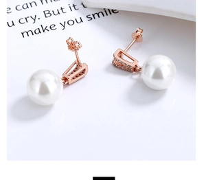 Détail du poinçon S925 sur des boucles d'oreilles en nacre or rose avec zircons brillants
