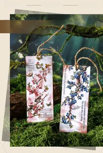 Close-up of vintage-style botanical gift tags with floral prints and twine on forest moss