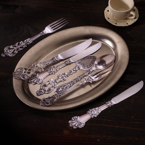 Set di posate vintage in acciaio inossidabile con rilievo barocco su tavolo in legno