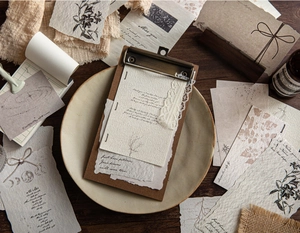 Makroaufnahme von Vintage-Scrapbook-Papier mit Pflanzendrucken und einem Holz-Klemmbrett