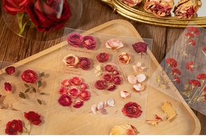 Detail of vintage floral PET stickers featuring roses and carnations on a wooden tray