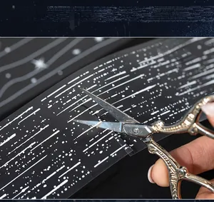 Macro shot of waterproof PET tape with starry meteor pattern being cut by vintage scissors