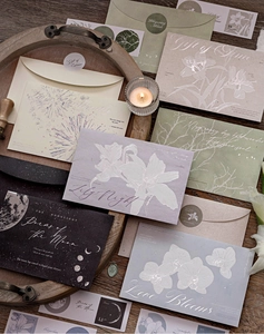 Close-up of vintage silver-stamped envelopes with floral and moon motifs on a tray