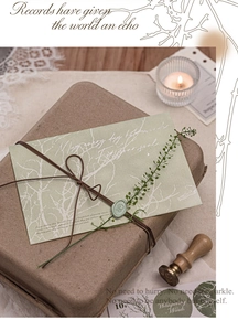 Detail of vintage kraft envelope with green wax seal and silver foil branch texture
