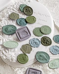 Detailed view of assorted vintage wax seals in muted tones on a decorative plaster tray