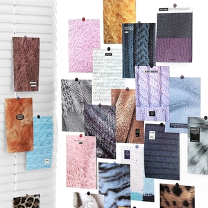 Artistic collage of colorful knitwear and faux fur fabric swatches on a white wall
