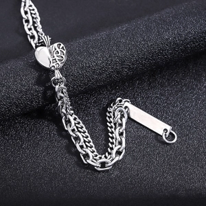 Detail of silver heart charm and engraved plaque on double-layer stainless steel chain
