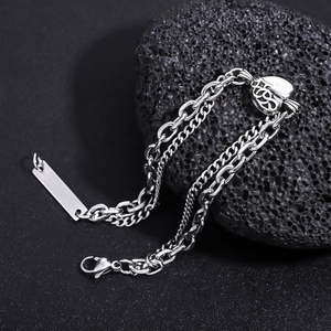 Detail view of silver double-layer heart chain bracelet on black volcanic rock