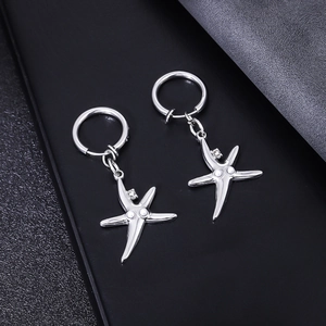 Détail de boucles d'oreilles étoile de mer avec perles et cristaux sur cuir noir