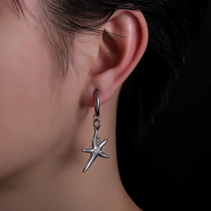 Boucle d'oreille en acier titane avec pendentif étoile de mer portée par un mannequin