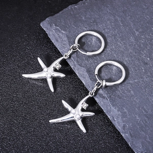 Boucles d'oreilles créoles étoile de mer argentées avec perles sur fond de pierre