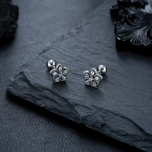 Macro detail of silver flower stud earrings with zircons and secure screw ball backs