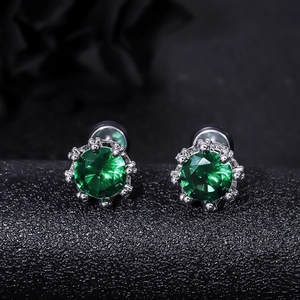 Macro shot of silver crown earrings with sparkling round green cubic zirconia studs