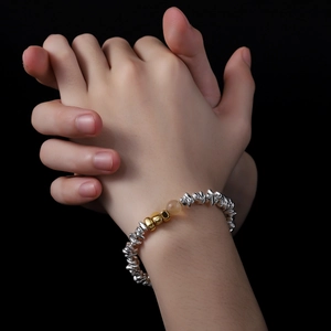 Silver textured beads bracelet with gold accents and yellow gemstone on a wrist