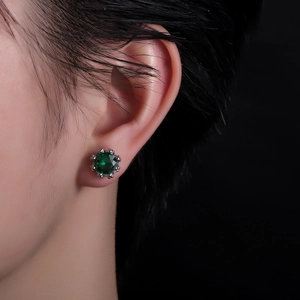 Macro shot of crown emerald stud earrings with green zircon and beaded silver setting