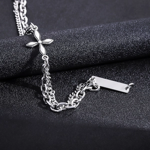 Macro detail of silver double-layered titanium steel bracelet with cross pendant on black leather