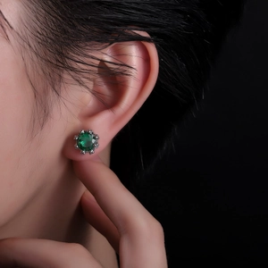Close-up of sparkling green zircon crown stud earring with claw setting on ear lobe