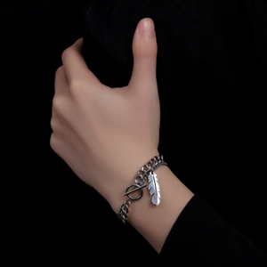 Detail of silver feather pendant on double-layer cuban chain with toggle clasp