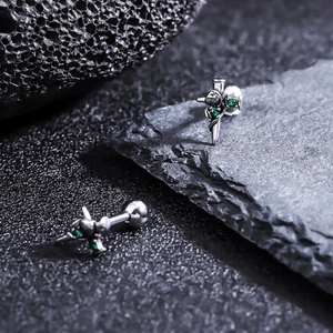 Macro shot of gothic sword and rose titanium stud earrings with green zircon accents