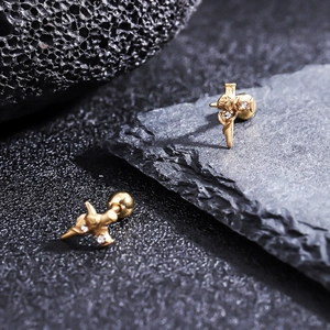 Golden rose and cross titanium earrings with cubic zirconia on black volcanic rock texture