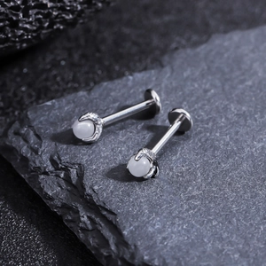 Macro detail of dragon claw stud earring with opal stone on a textured stone surface