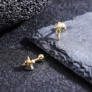 Macro shot of gold-plated cross earrings with green zircon and ball back closures