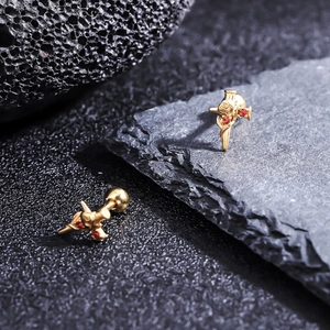 Close-up of gold titanium ear studs featuring a cross floral design with red zircon stones